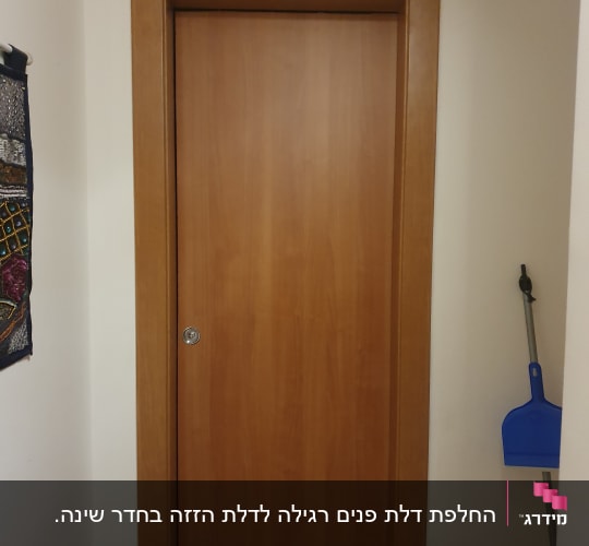 דלת עץ חומה עם מסגרת עץ וקיר לבן
